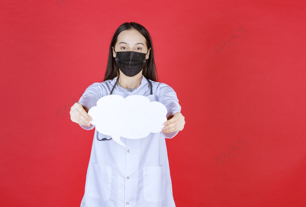 居家女医生带着听诊器 戴着黑色面罩 手里拿着一张云状的空白问讯台健康治疗诊所