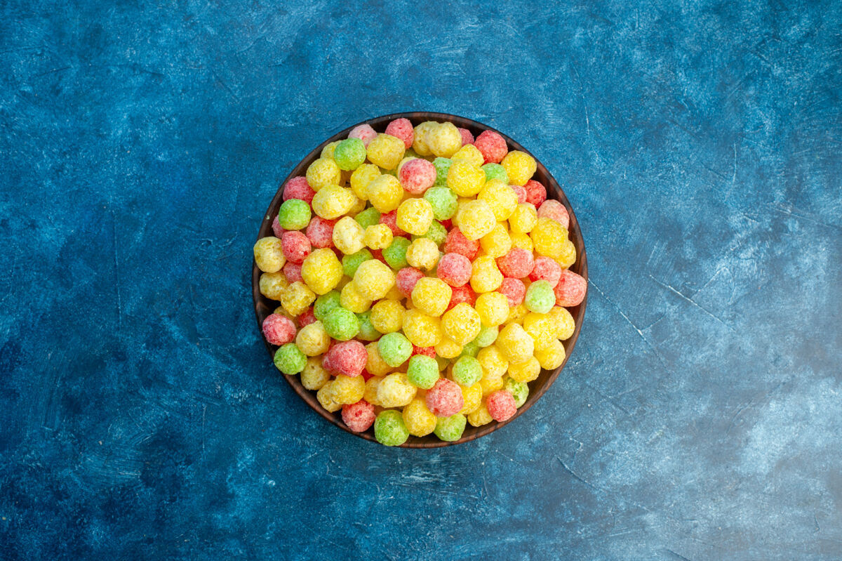 葡萄在蓝色背景的棕色小锅里放着美味的彩色糖果食品多汁水果