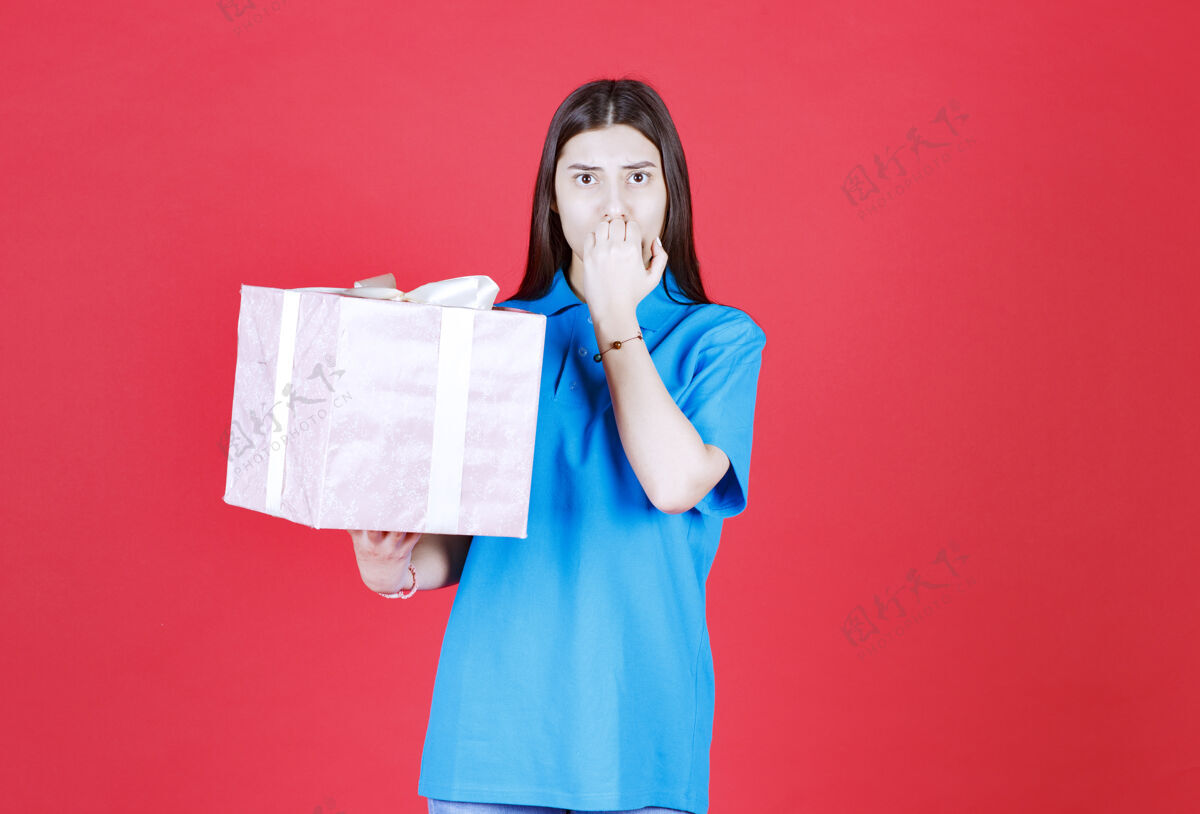 女人一个女人拿着一个紫色的礼盒 看起来很困惑 很有思想不确定激动礼物