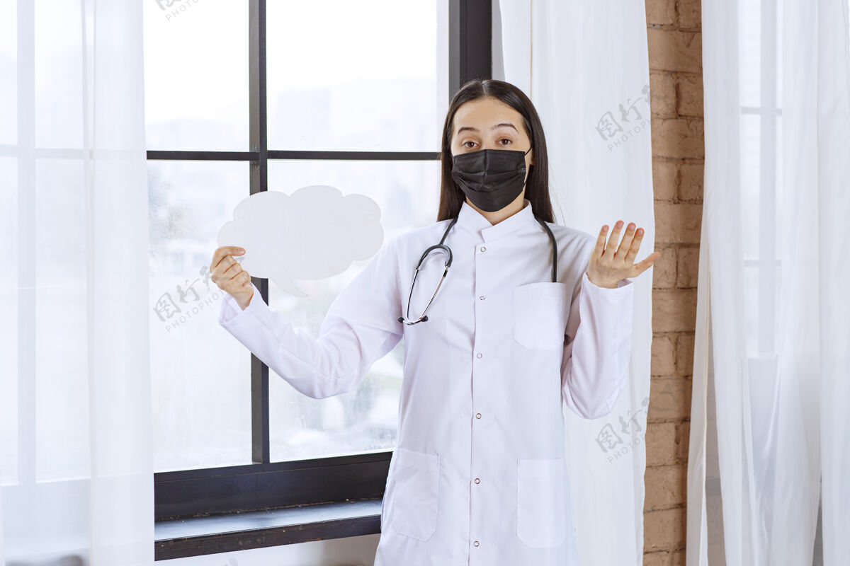 紧张医生拿着听诊器和黑色面罩 手里拿着一块白云形状的思考盘 看上去很困惑信息制服项目