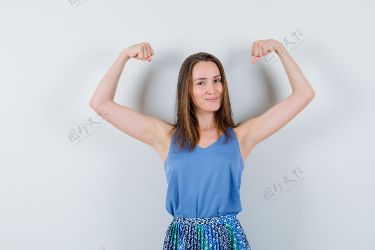 健康年轻的女士展示了手臂的肌肉在单打 裙子和看起来自信皮肤护理手臂干净