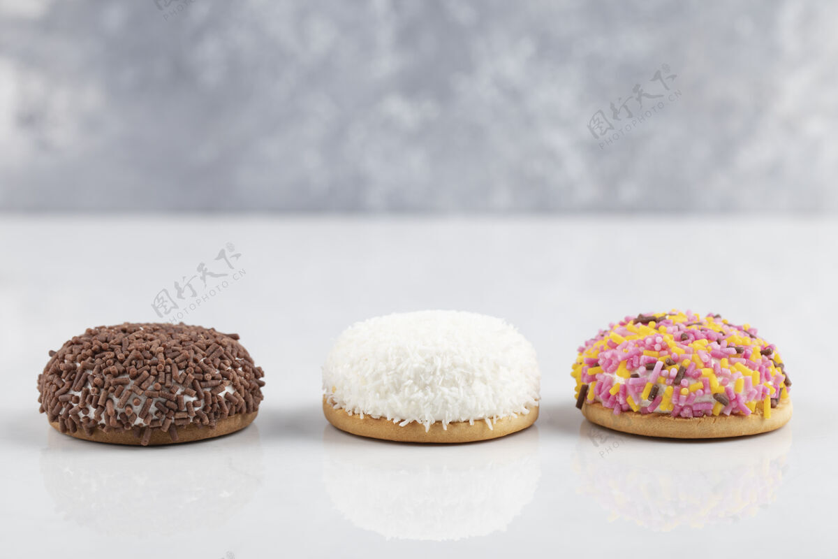 蓬松圈甜棉花糖饼干与洒在白色表面含糖糖果美味