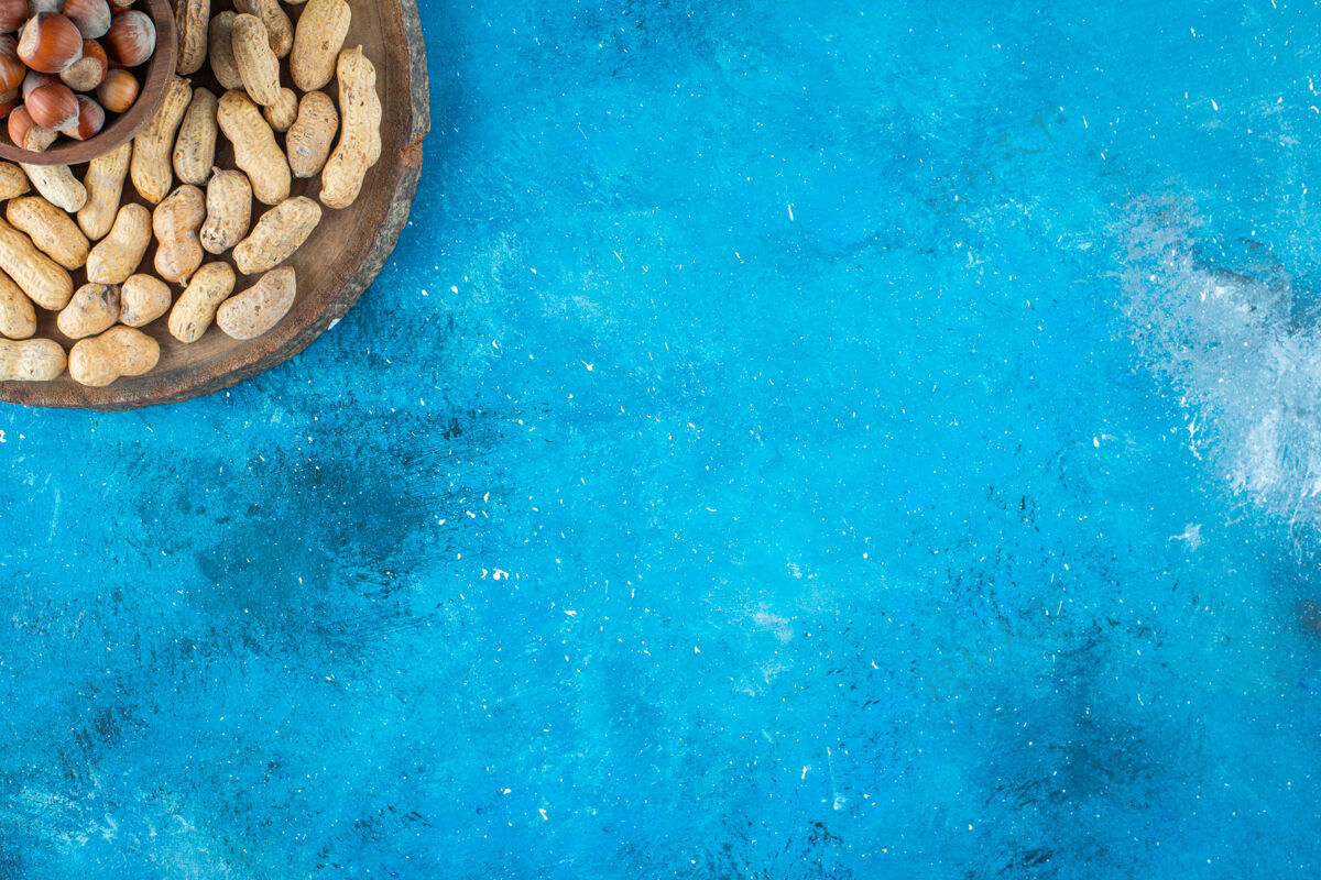 碗把榛子放在碗里 在蓝色的表面放上花生榛子健康美味