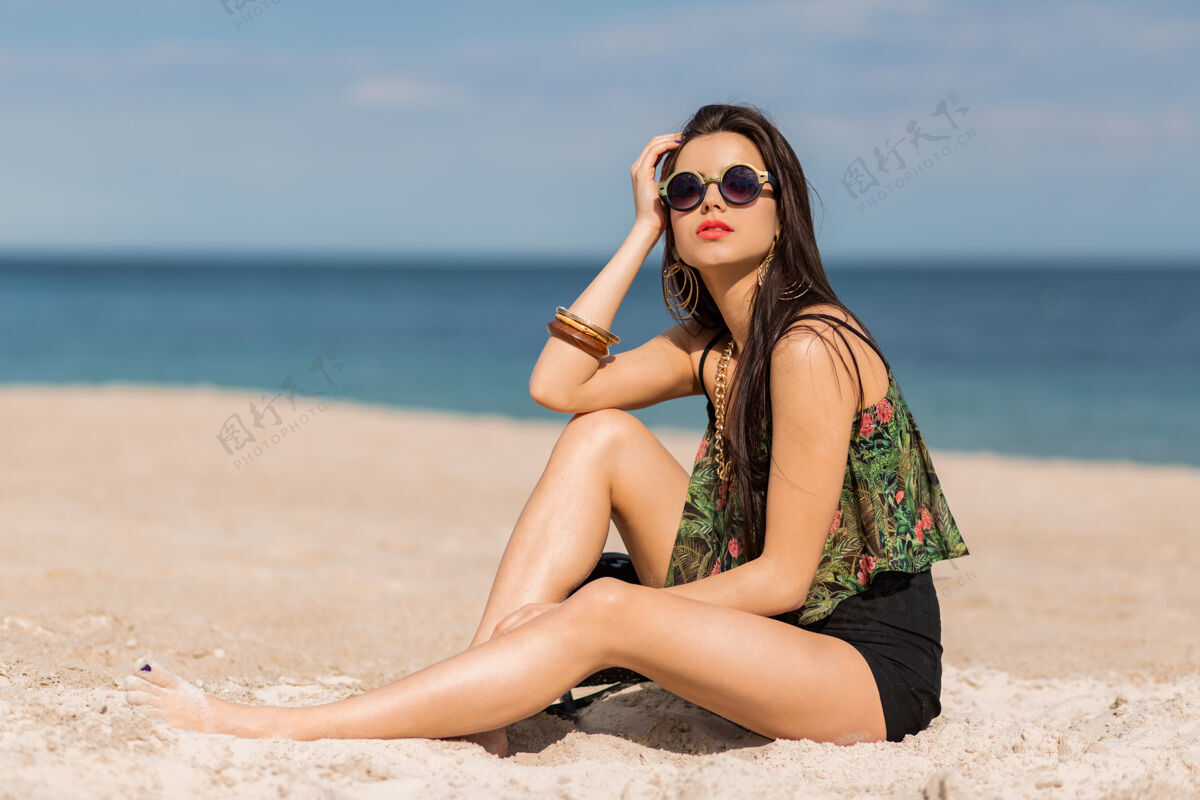 心情穿着时髦的热带服装的女人在海滩上摆姿势放松酷女性