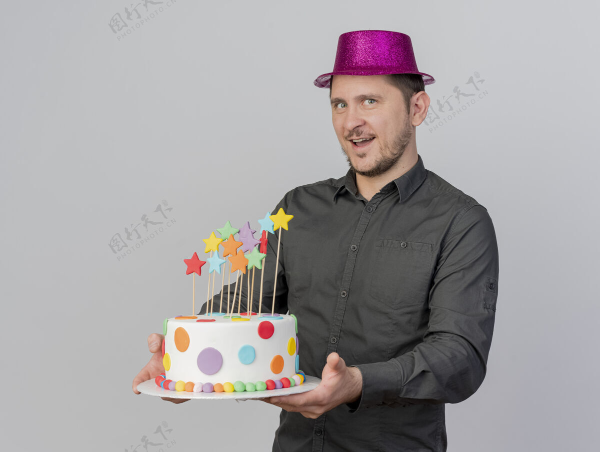 蛋糕微笑着的年轻人戴着粉红色的帽子拿着蛋糕孤立在白色的背景戴着小伙子抱着
