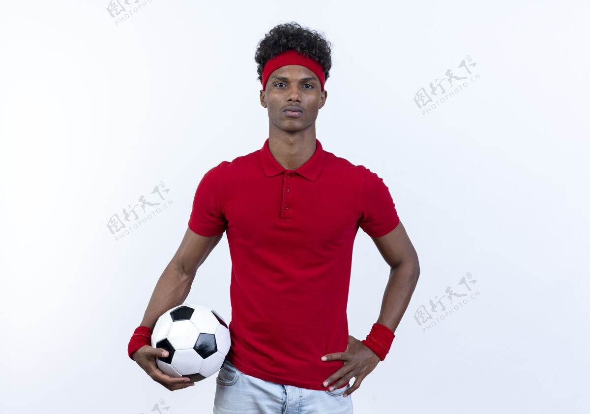 手自信的美国黑人年轻运动男子戴着海带和腕带拿着球 把手放在臀部隔离在白色背景上自信年轻运动