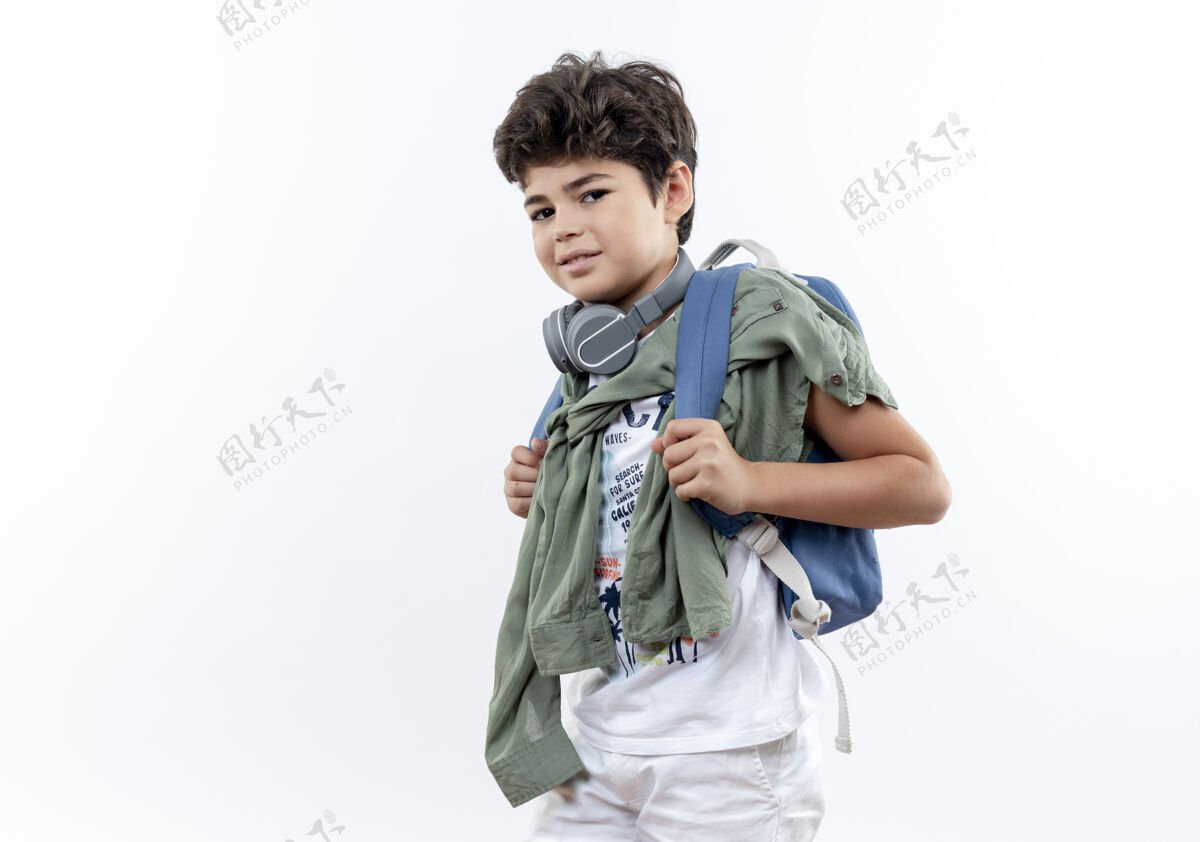 小男孩高兴的小男孩戴着背包和耳机隔离在白色背景上包耳机请戴上