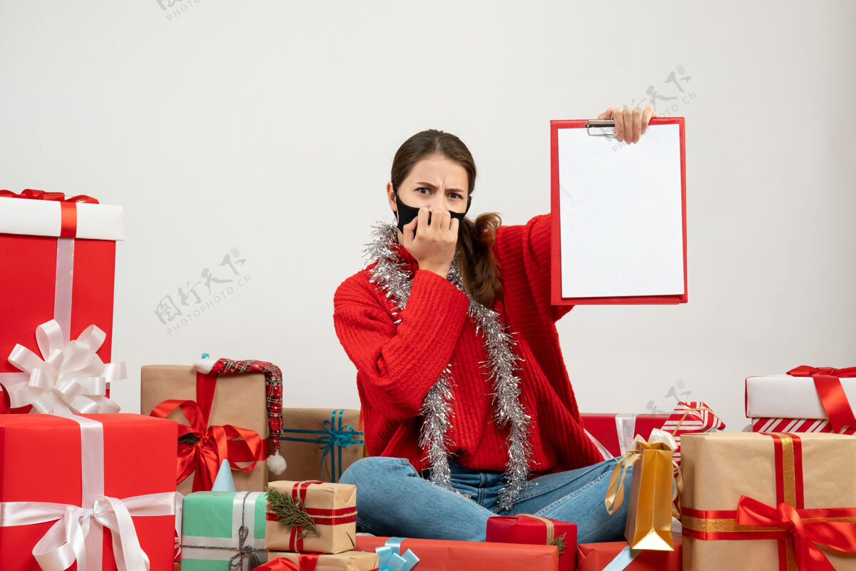 房子前视图困惑的女孩戴着黑色面具拿着文件坐在礼物周围抱着成人微笑
