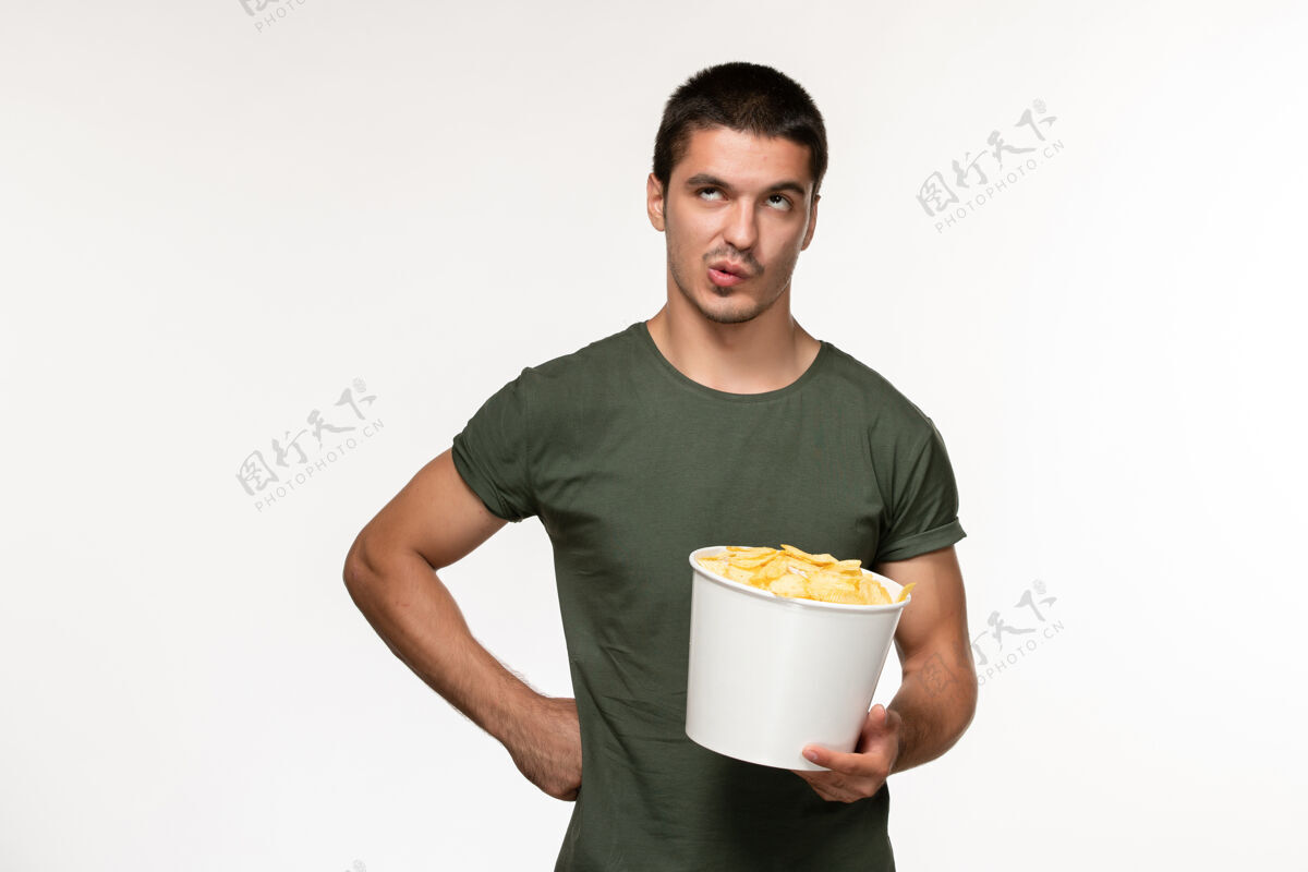 电影正面图身穿绿色t恤的年轻男性 浅白色墙壁上有土豆cips电影人男性孤独电影电影院年轻男性成人浅白色