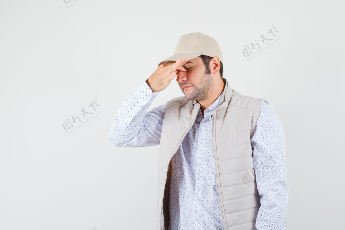 疲惫年轻人穿着米色夹克 戴着帽子 用手捂住脸上的一部分 看上去很累 前视图脸年轻肖像