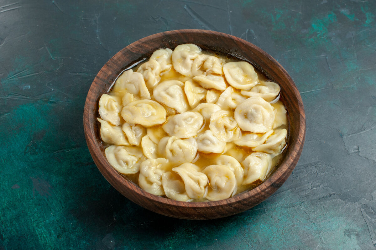 汤俯瞰美味的饺子汤在深绿色桌子上的棕色盘子里食物蔬菜汤肉面团玉米风景饺子