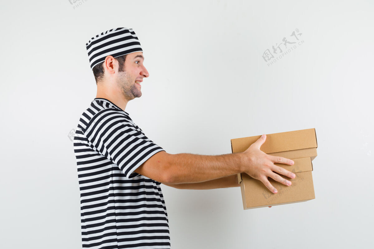 脸年轻的男人送着纸箱 穿着t恤 戴着帽子 看上去很快乐肖像人年轻人