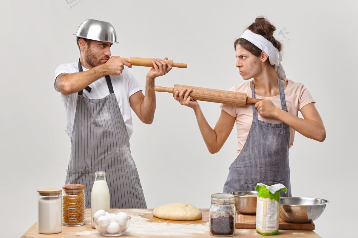 烹饪横拍愤怒的夫妻感觉自己像对手 用擀面杖互相射击 在家一起做饭 用面粉做面团 准备美味的糕点 做面包厨房打架制服男朋友比赛