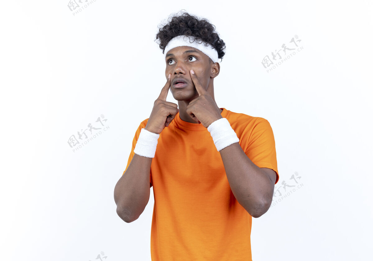 运动看着身边悲伤的年轻黑人运动男子戴着头带和腕带睁开眼睛手指孤立在白色背景上穿手指悲伤