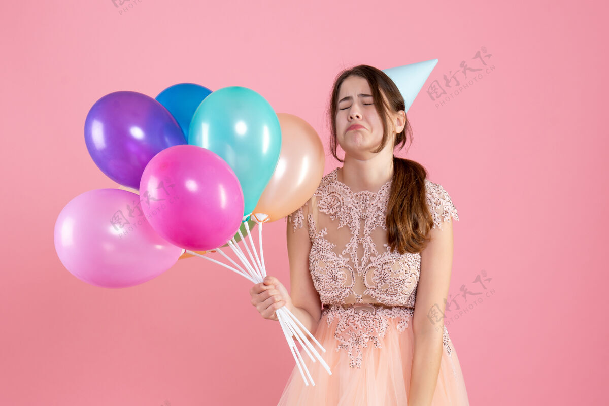 乐趣前视图哭泣的女孩与党帽举行气球粉色气球欢呼