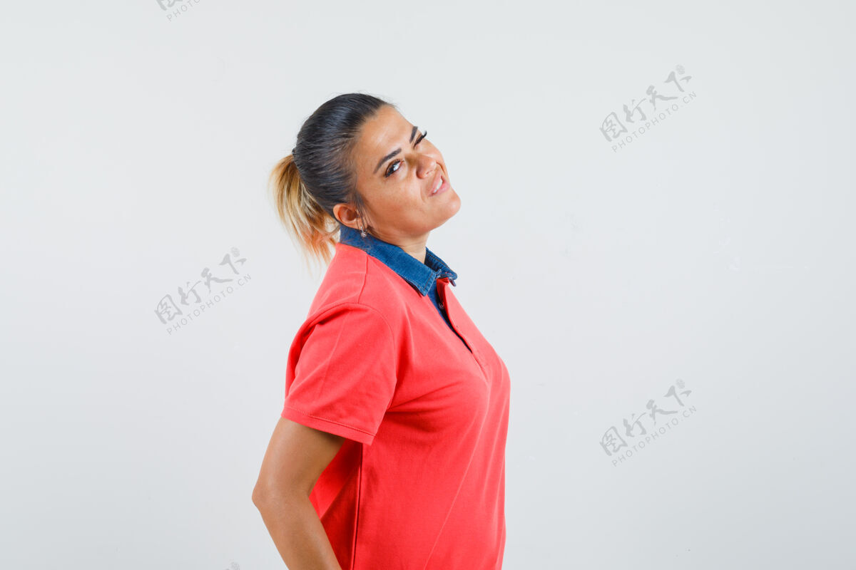护理年轻女子站直了 回头望去 穿着红色t恤摆出一副恼火的样子正视图微笑可爱前面