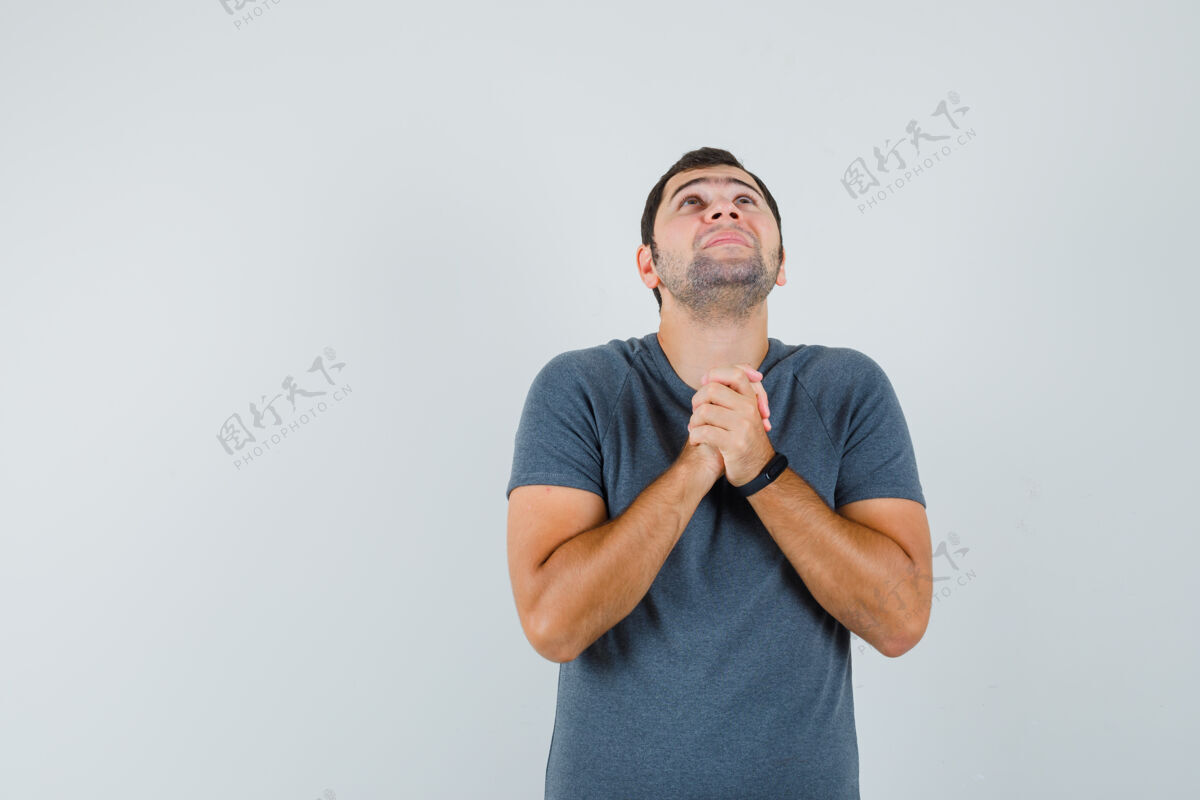 商务网络摄像头身穿灰色t恤的年轻男子双手合十祈祷 看上去充满希望男孩信心祈祷