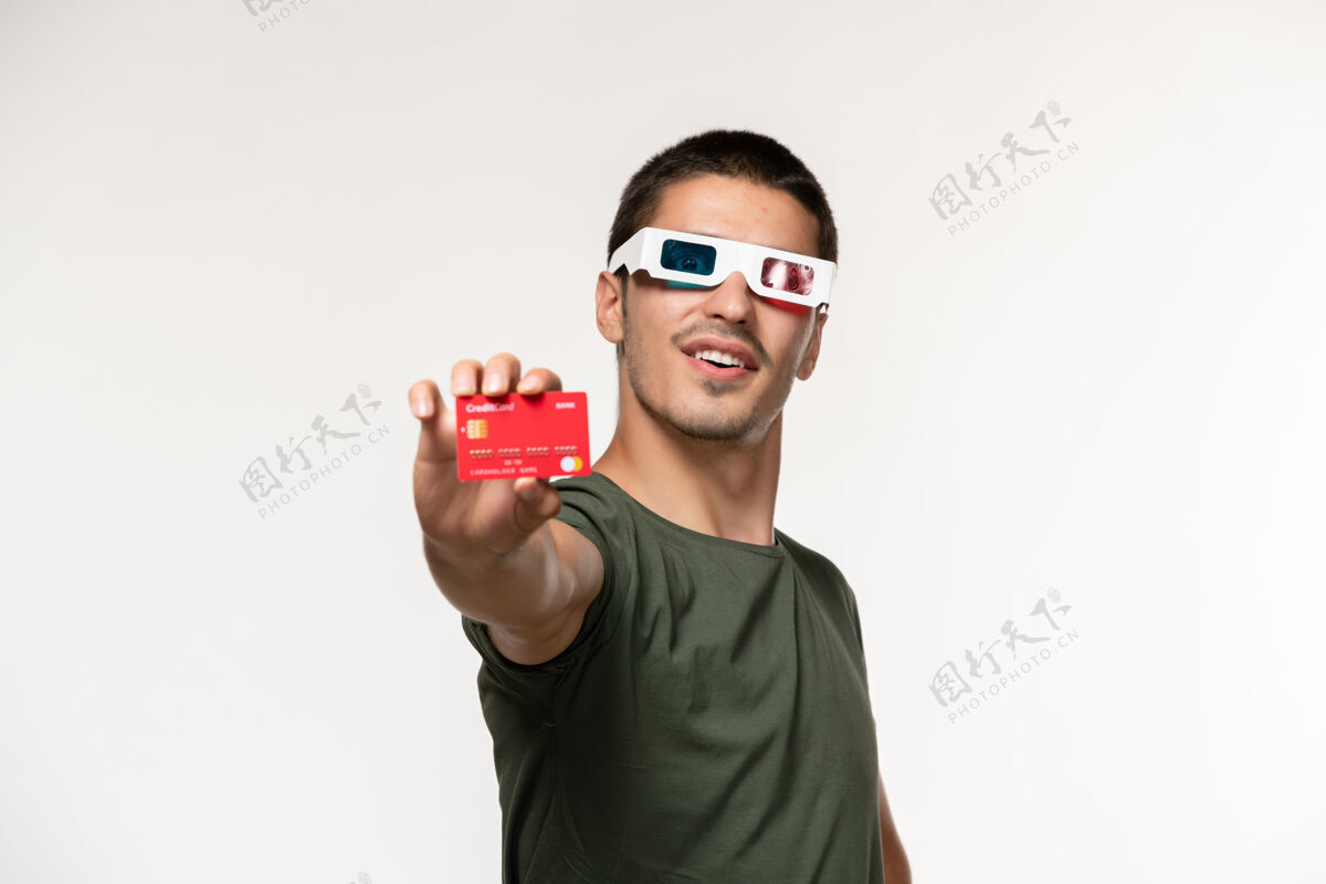 电影正面图身穿绿色t恤的年轻男子戴着d墨镜拿着银行卡在浅白的墙上看电影孤独的电影院电影银行观点