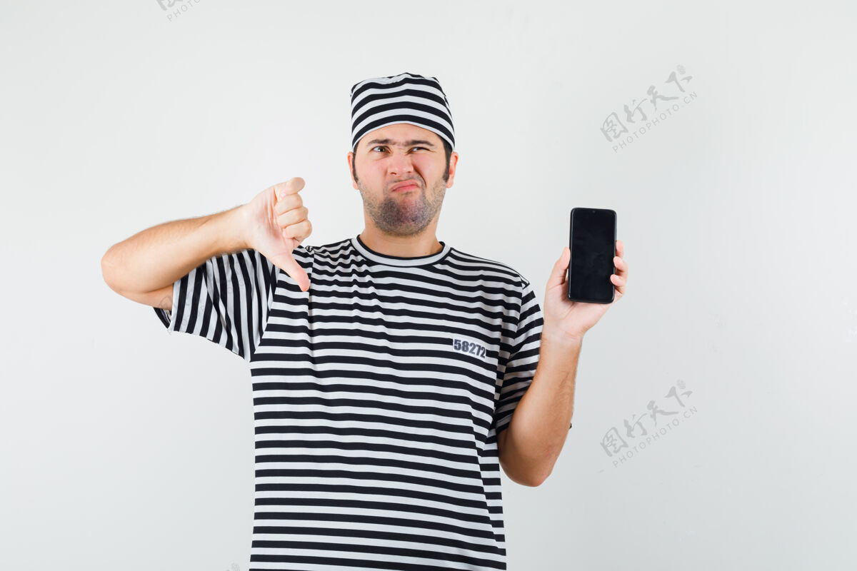 按住男青年穿着t恤 戴着帽子拿着手机 大拇指朝下 神情不悦 前视图脸显示手机