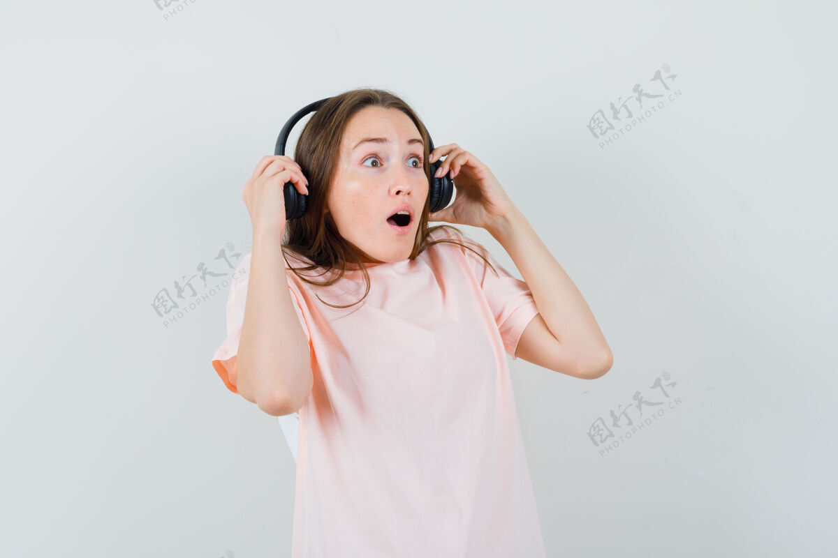 耳机穿着粉色t恤的年轻女孩摘下耳机 看上去很惊讶可爱搞笑头发