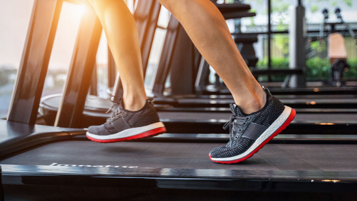 慢跑穿着运动鞋在健身房跑步机上跑步的男性脚运动概念训练教练身体