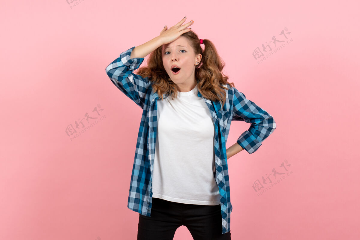 年轻正面图穿着格子衬衫的年轻女性在粉色背景上摆出困惑的表情年轻女性色彩情感模特儿肖像表情微笑