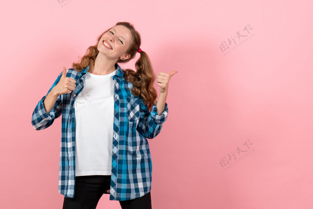 年轻女性正面图身着蓝色格子衬衫的年轻女性在粉色背景上微笑摆姿势情感女孩模特时尚青年小子格子成人孩子