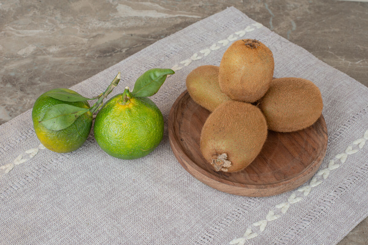桌布在灰色桌布上放上奇异果和新鲜橘子天然水果叶子