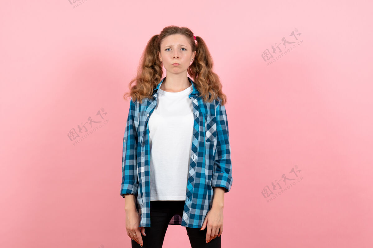 姿势正面图身着蓝色格子衬衫的年轻女性在粉色背景上摆出疯狂的表情女性情感女孩色彩模特时尚格子情绪女孩