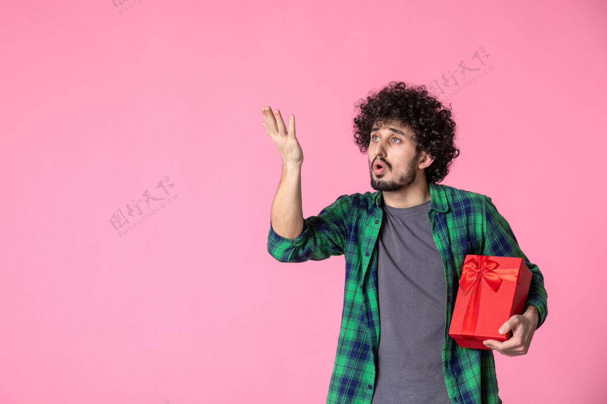 蝴蝶结浅粉色墙上红色包裹的年轻男性正面图礼盒文案红色包装