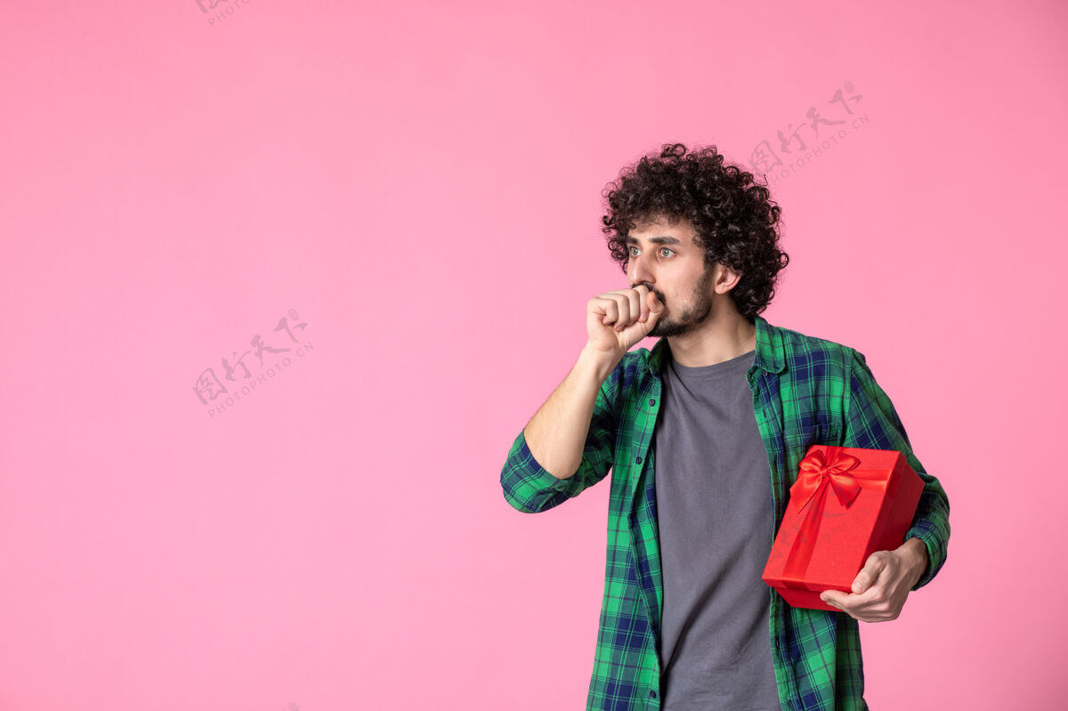 文案浅粉色墙上红色包裹的年轻男性正面图蝴蝶结衬衫年轻人