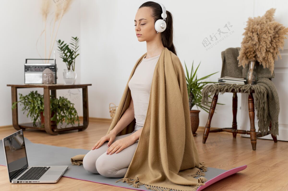 耳机戴着耳机在家冥想的女人禅宗瑜伽笔记本电脑