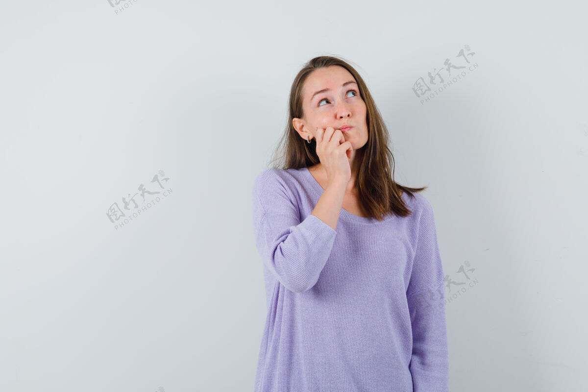 女士年轻的女性看着左上角 一边想着什么 一边穿着淡紫色的衬衫 看起来很困惑思考手拼图