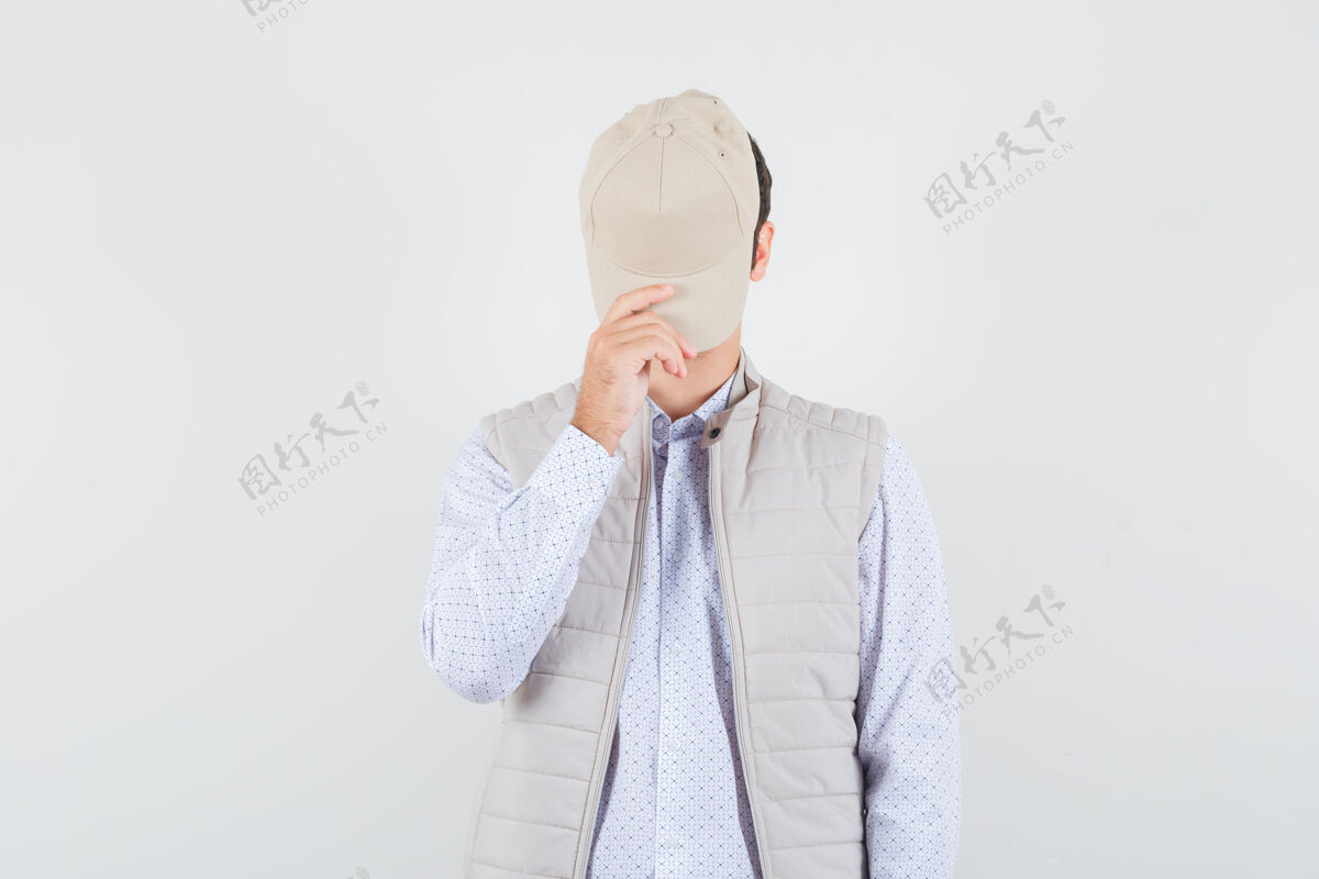 脸一个年轻人戴着帽子 穿着衬衫 无袖夹克 看上去很神秘正面图夹克男人自然