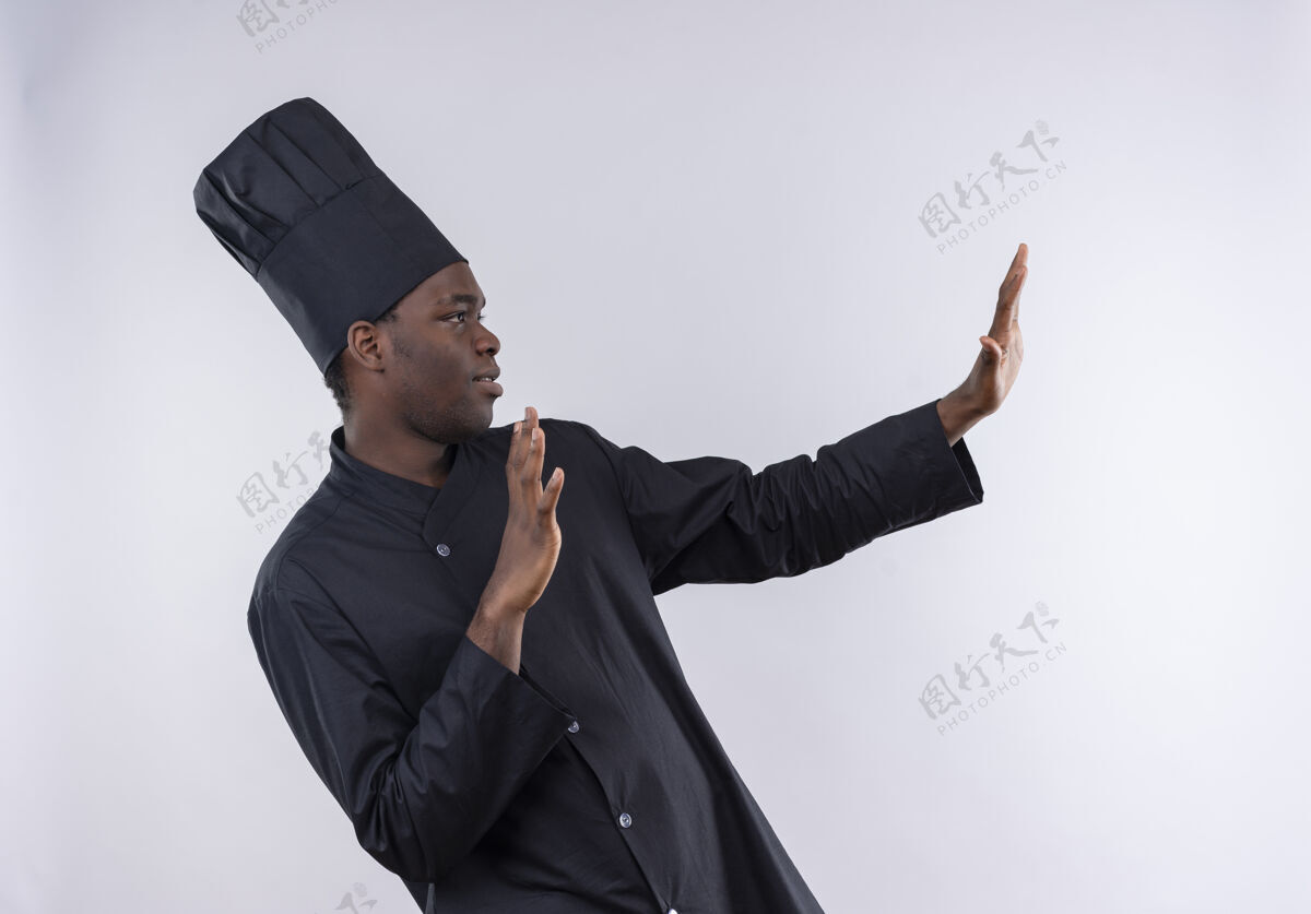 厨师年轻自信的非洲裔美国厨师身着厨师制服 双手放在白色的复制空间上假装防守非裔美国人假装自信