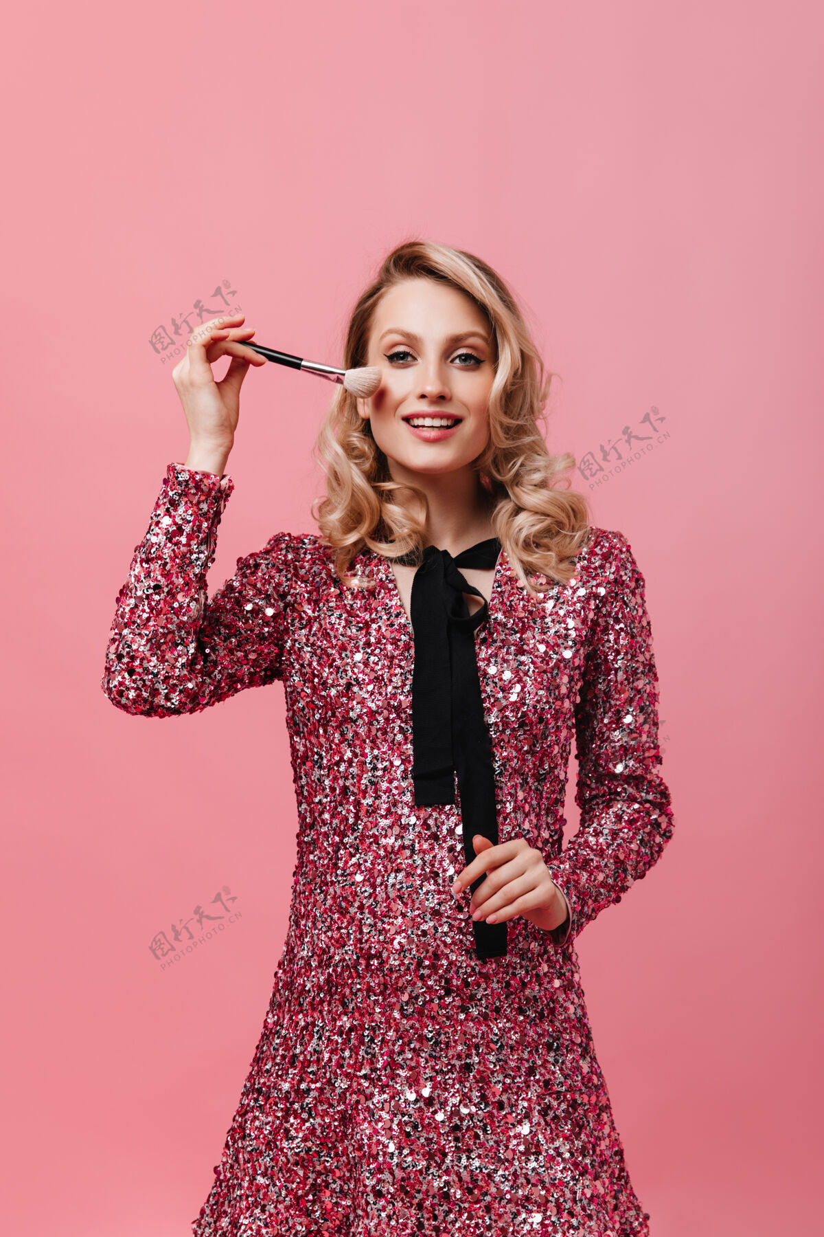 时尚一个穿着粉色裙子的年轻女人 手里拿着蓬松的化妆刷化妆长袍美丽