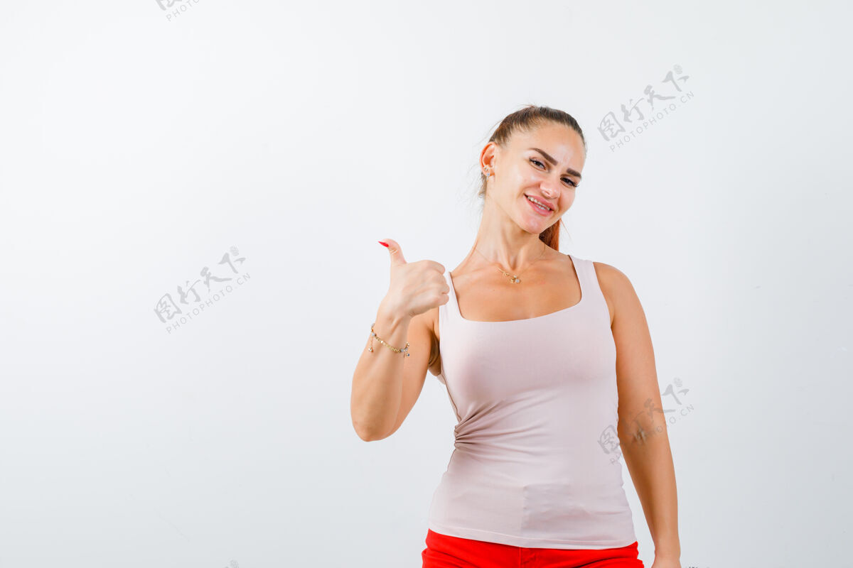 模特年轻女士在米色背心上竖起大拇指 看起来很高兴 正面视图坦克皮肤护理健康