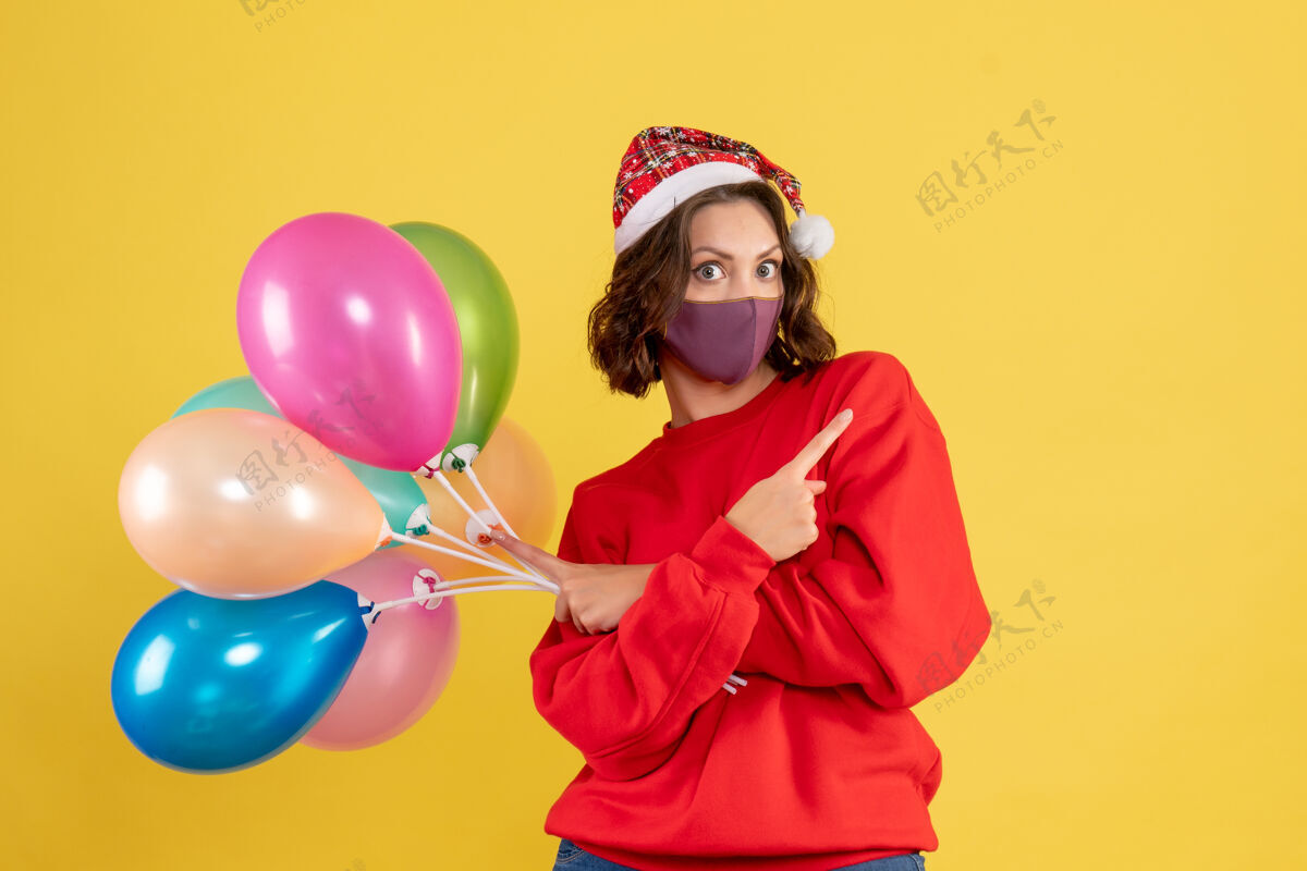 年轻女子正面图年轻女子手持黄色气球气球庆祝外科口罩
