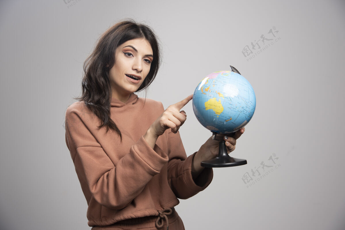 女人黑发女人指着地球上的小地方成人工作肖像