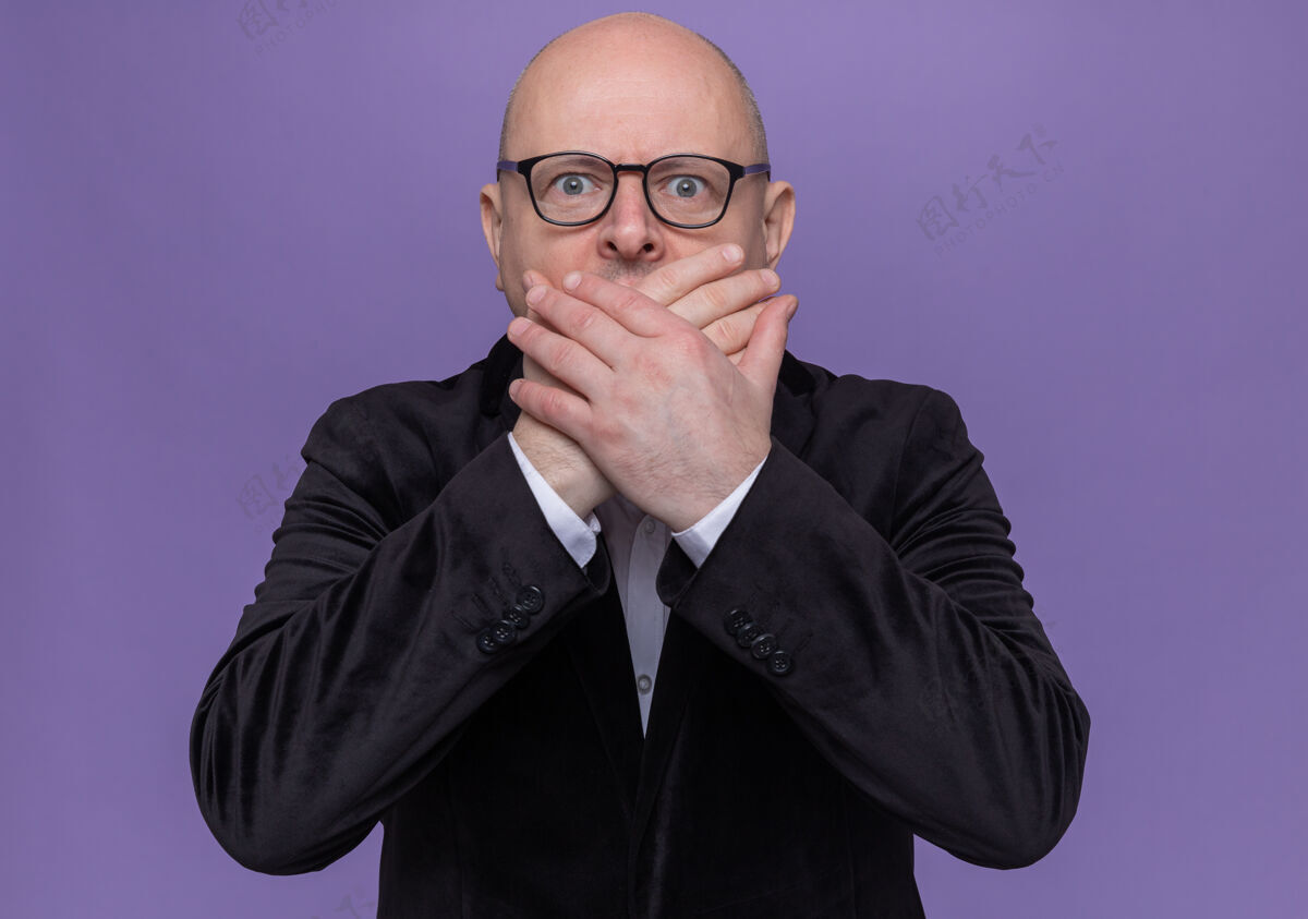 男人中年光头西装革履 戴着眼镜望着前面 吓得捂着嘴站在紫色的墙上手西装眼镜