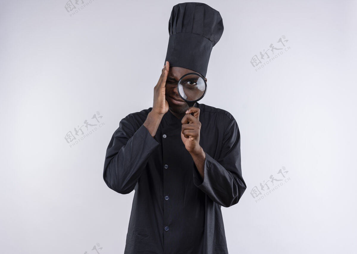 厨师年轻焦急的非洲裔美国厨师身着厨师制服 透过放大镜或放大镜在白色地板上观看 并留有复印空间烹饪玻璃复制