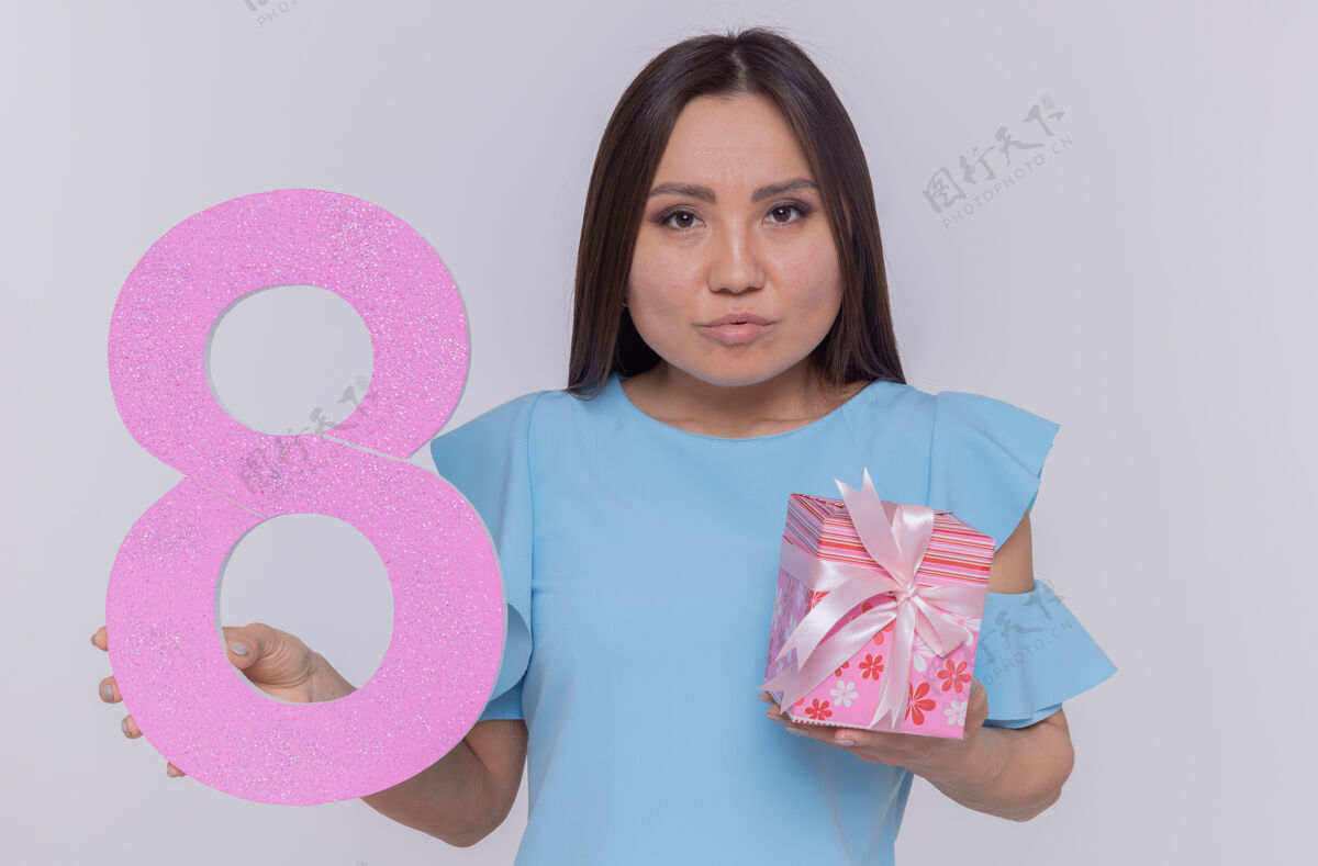 女人一位身穿蓝色连衣裙的亚洲妇女手持纸板做的8号 站在白色的墙上 严肃地看着前面庆祝国际妇女节庆祝站制造