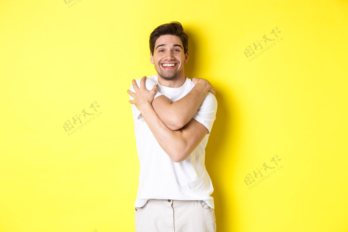 男人快乐善良的家伙拥抱着自己 微笑着 高兴地站在黄色背景下复制空间成人表情帅气