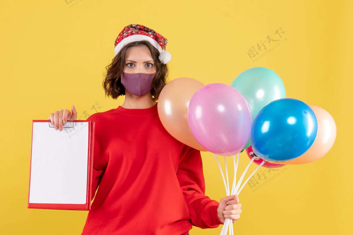 外科口罩正面图年轻女子手持气球和文件说明黄色病毒冠状病毒党的情感新年彩女派对病毒气球