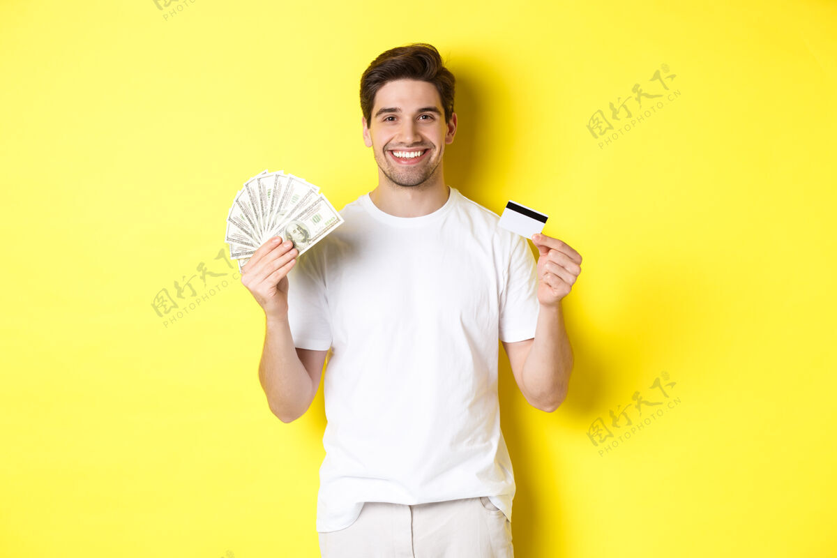 时尚年轻人从信用卡里取钱 微笑着高兴 站在黄色的背景上有钱金钱帅气