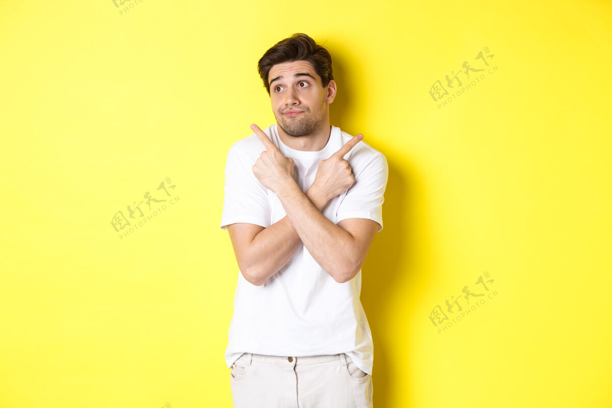 自信优柔寡断的男人耸耸肩 指指点点 纠结地选择 站在黄色的背景上工作室男人站