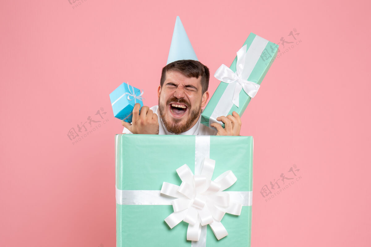 睡眠正面图：年轻男性站在粉红色书桌上的礼品盒内 彩色睡衣派对照片 情感睡眠圣诞颜色购物礼物