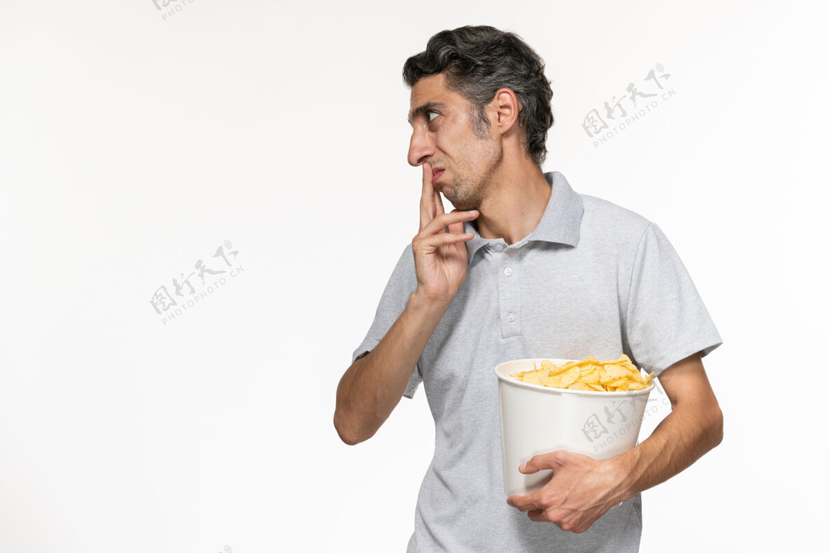 篮子正面图：年轻的男性拿着一个篮子 里面放着薯片 和一个在白色表面上的人说话遥远电影院抱着