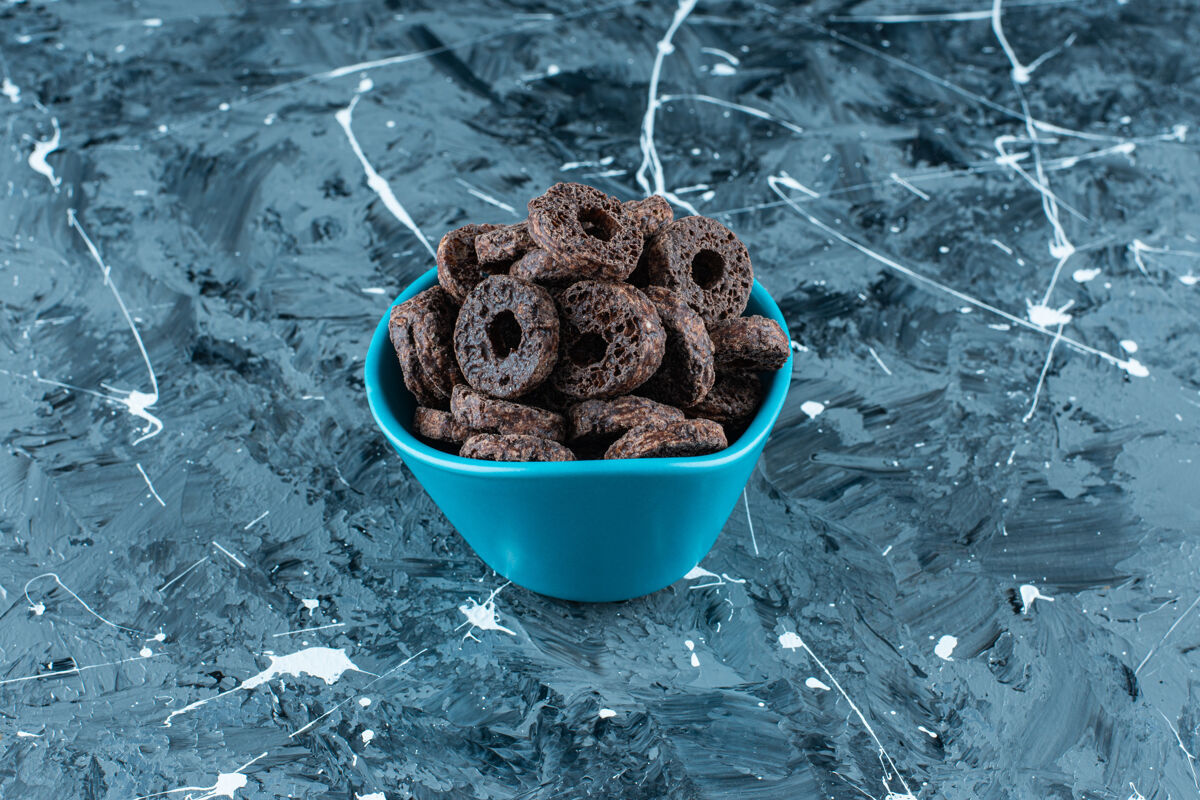 糖美味的巧克力涂层玉米圈在一个碗里 在大理石背景上牙套可口碗