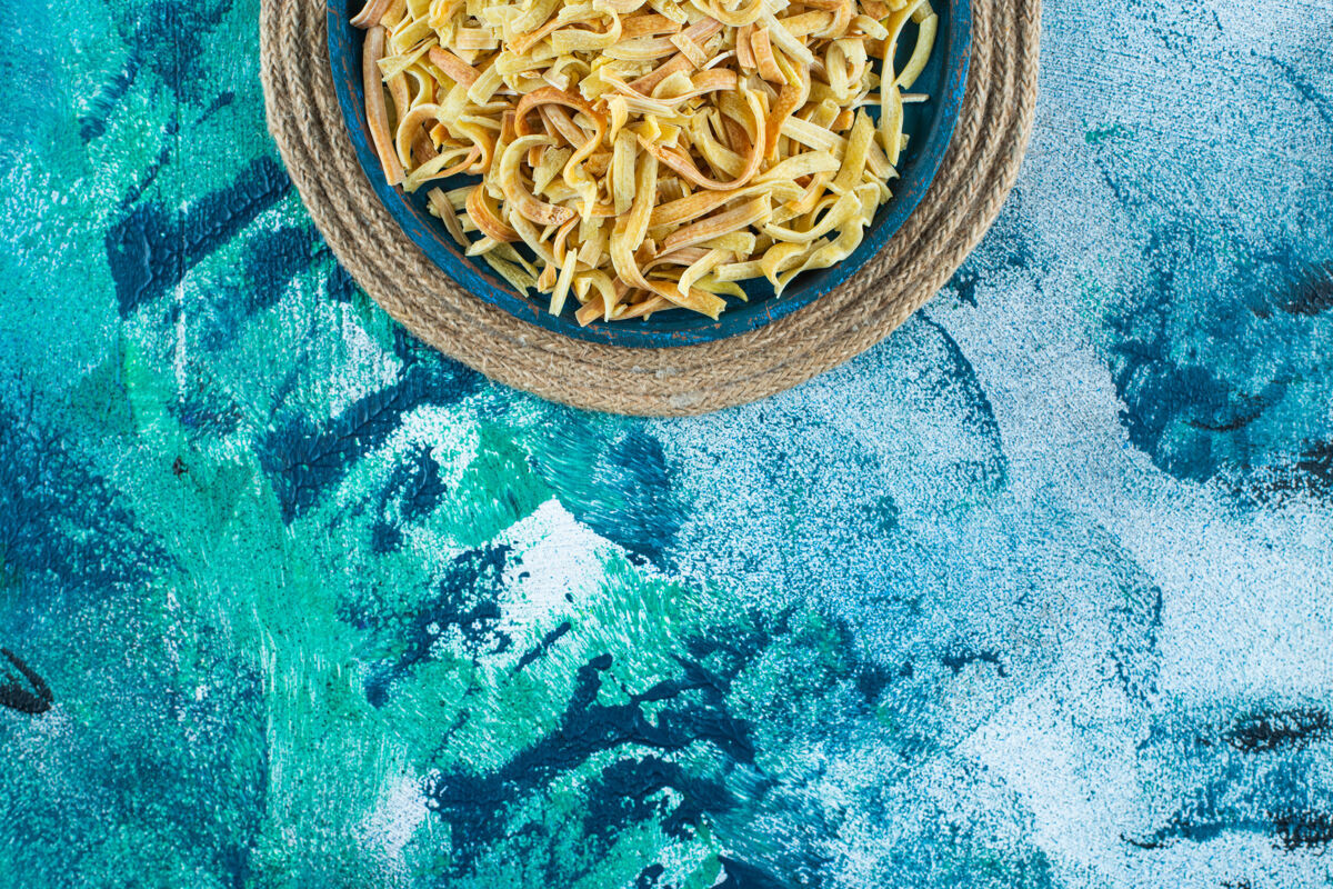 意大利料理碗里的面条放在三角架上 蓝色背景美味自制美味